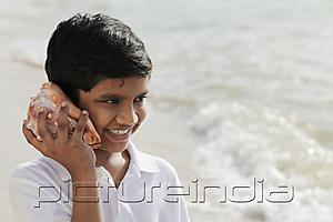 PictureIndia - Young boy listening to sea shell