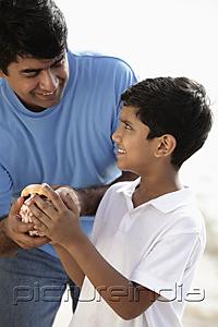 PictureIndia - Father and son holding sea shell and smiling