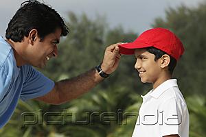 PictureIndia - Father putting on son's baseball cap.