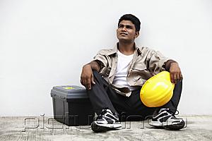 PictureIndia - man sitting on ground holding construction hat