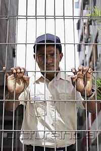 PictureIndia - Security guard holding fence and staring