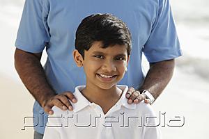 PictureIndia - Cropped shot of father's hands on smiling son's shoulders