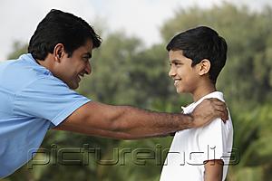 PictureIndia - Father and son looking at each other and smiling outdoors.