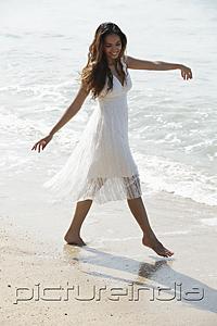 PictureIndia - young woman dancing on the sand at the beach