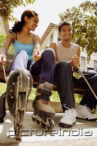 PictureIndia - Man and woman lacing up roller blades