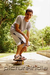 PictureIndia - Man balancing on skateboard, looking at camera