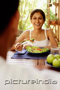 PictureIndia - Woman eating salad, looking at man across from her