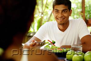 PictureIndia - Man looking at person opposite him, salad in front of him