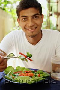 PictureIndia - Man eating salad, looking at camera