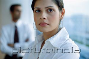 PictureIndia - Female executive looking at camera, people in the background