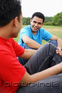 PictureIndia - Two men sitting side by side in park, talking