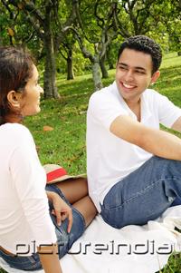 PictureIndia - Couple in park, sitting on picnic blanket, looking at each other