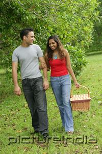 PictureIndia - Couple walking in park, arm in arm, woman carrying picnic basket
