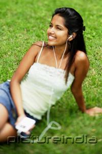 PictureIndia - Young woman listening to music with headphones, portrait