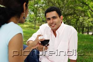 PictureIndia - Couple toasting with wine glasses, man looking at camera