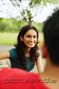 PictureIndia - Woman smiling, facing another person, over the shoulder view
