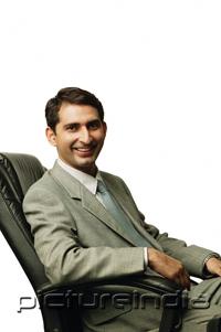 PictureIndia - Businessman sitting on chair, smiling at camera
