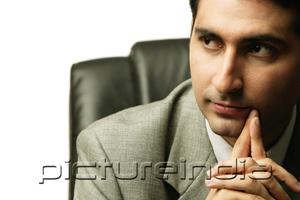 PictureIndia - Businessman sitting, looking away, hands clasped