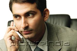 PictureIndia - Businessman holding mobile phone, looking away