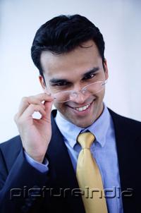 PictureIndia -  Businessman adjusting glasses, smiling at camera