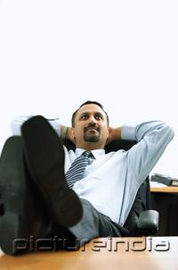 PictureIndia - Businessman in office, hands behind head, feet on desk