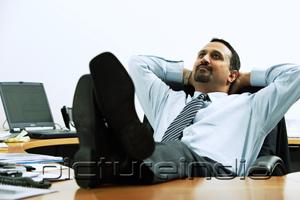 PictureIndia - Businessman with feet on desk, hands behind head