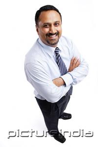 PictureIndia - Businessman looking up at camera, arms crossed