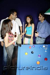 PictureIndia - Young adults standing around pool table