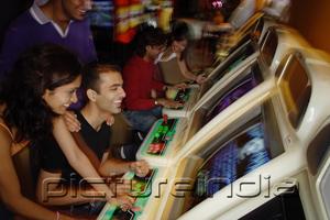 PictureIndia - Young adults playing games in video arcade