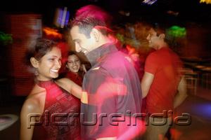 PictureIndia - Young people dancing in night club, couple in the foreground