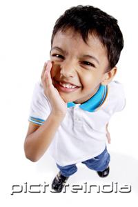 PictureIndia - Young boy looking up at camera, hand on chin