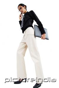 PictureIndia - Business woman using mobile phone, carrying folder, looking at camera, low angle view