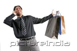 PictureIndia - Businessman using mobile phone, carrying shopping bags