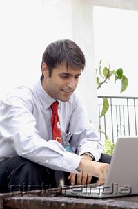 PictureIndia - Businessman sitting in patio, using laptop