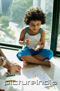 PictureIndia - Girl sitting on floor with crayons and paper, fathers hands in foreground
