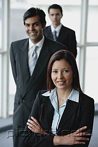 PictureIndia - Businesswoman smiling at camera, businessmen behind her